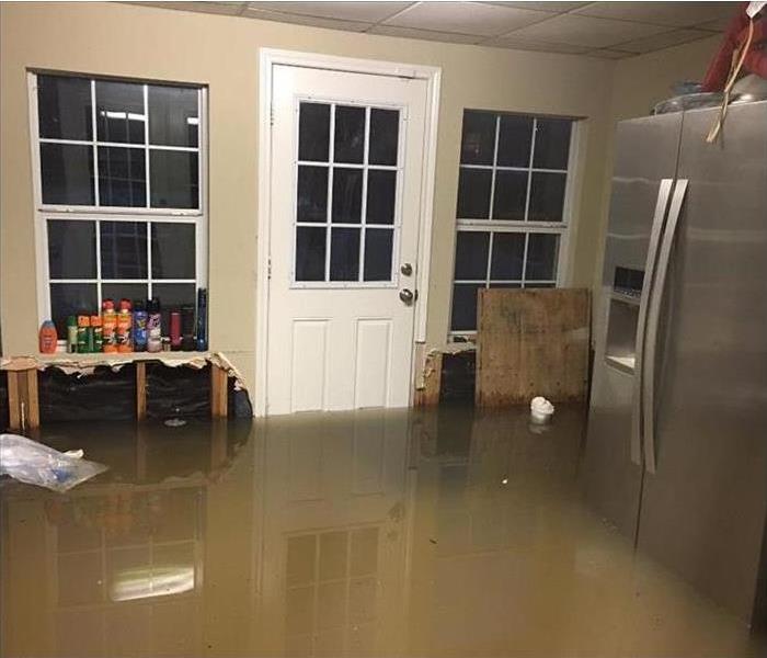 filthy floodwater covering floor and bottom of a refrigerator