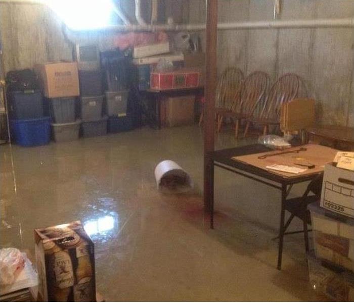 water in basement, chairs and stacked plastic containers in corner