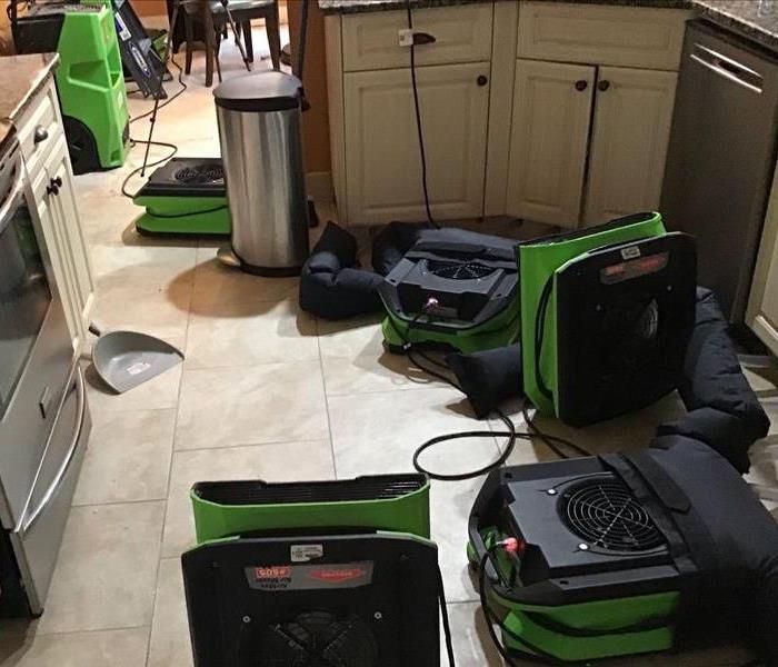 A kitchen with injecta-drys, air movers, and a dehumidifier in the room, set to properly dry the area.