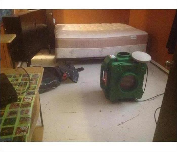 A bedroom with an air scrubber in the middle of the floor after a fire